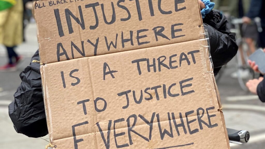 Image of person holding cardboard sign about injustice